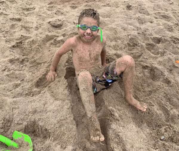 Child sitting on a sandy beach with legs stretched out in Brownsburg, IN
